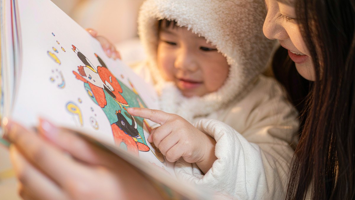 孩子指着绘本说给妈妈听