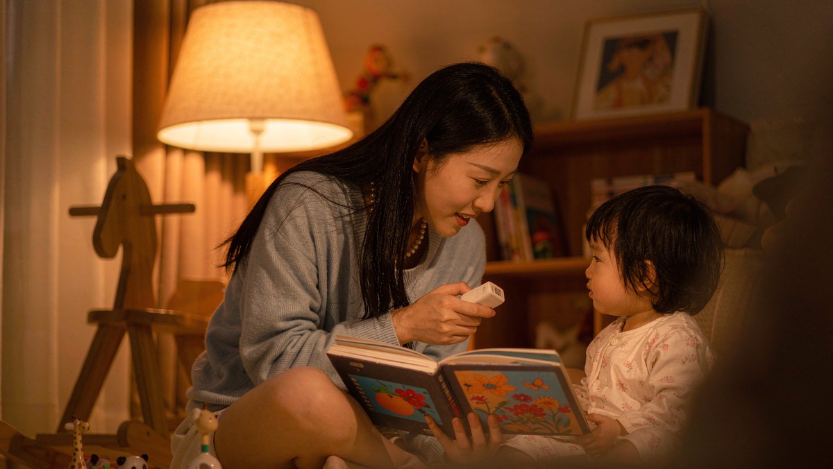 夜灯下家长合上故事机陪孩子读绘本