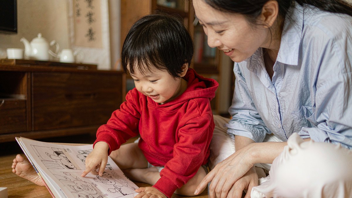 孩子指着绘本画面认真向妈妈提问