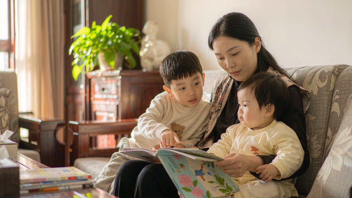 妈妈在沙发上给两个孩子一起读绘本
