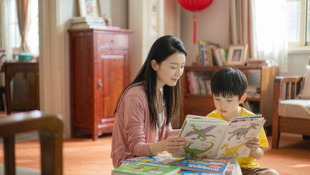 妈妈坐在孩子旁边陪他一起看恐龙绘本