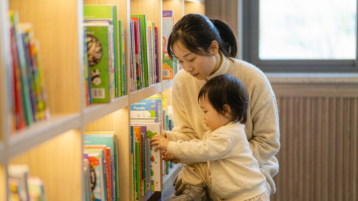 妈妈和孩子在图书馆书架前挑选绘本