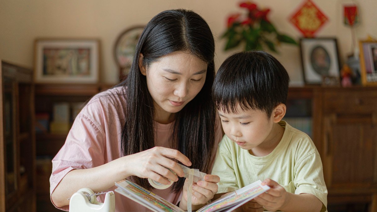 妈妈和孩子一起用胶带修补撕坏的绘本