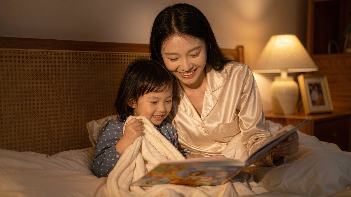 妈妈在床头搂着女儿读完绘本准备关灯