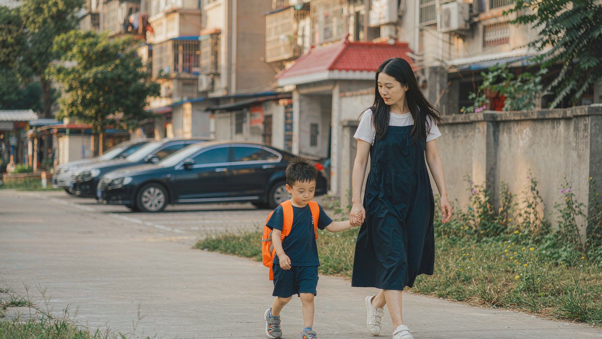 妈妈牵着孩子走在小区路上一边聊天