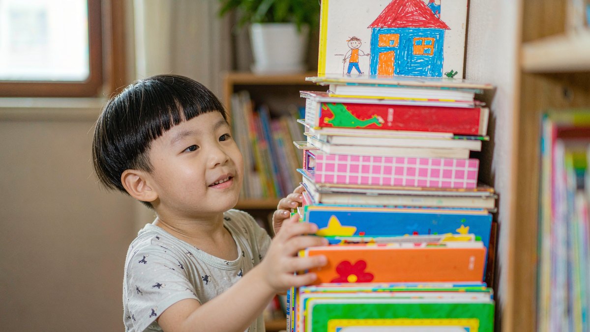 孩子把自己读过的绘本摞成一叠合影