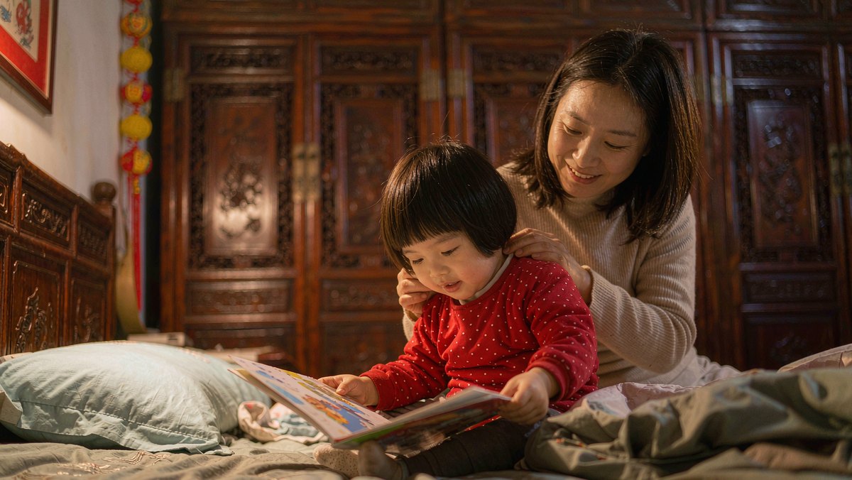睡前孩子安静地抱着绘本，妈妈陪在身边