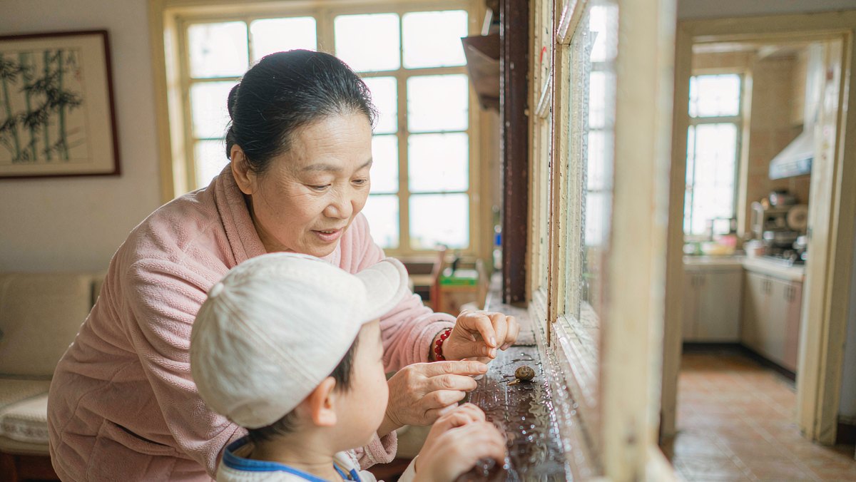 妈妈和孩子一起在窗边观察下雨后的小蜗牛