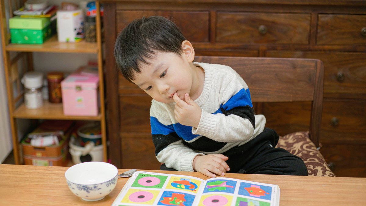 亲子坐在桌前，孩子歪着头认真思考妈妈问的问题