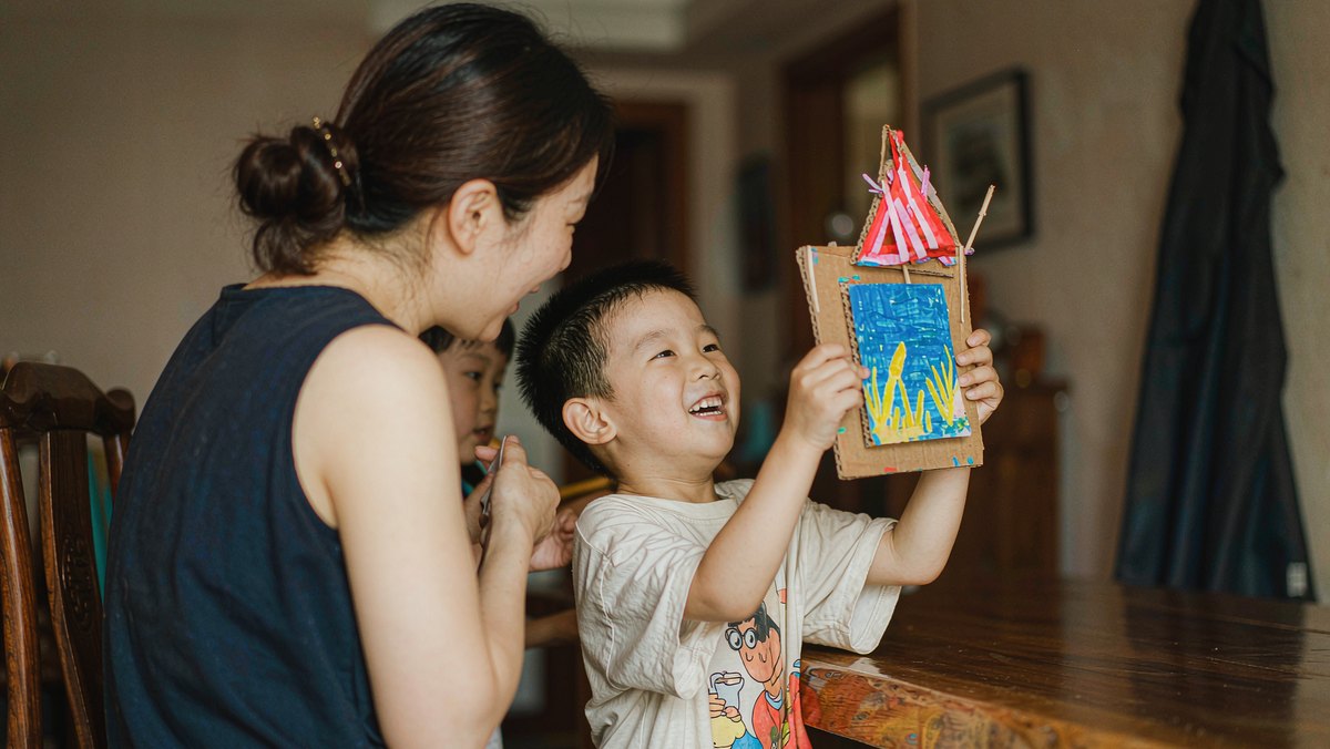 孩子举着自己做的手工，兴冲冲地讲给妈妈听