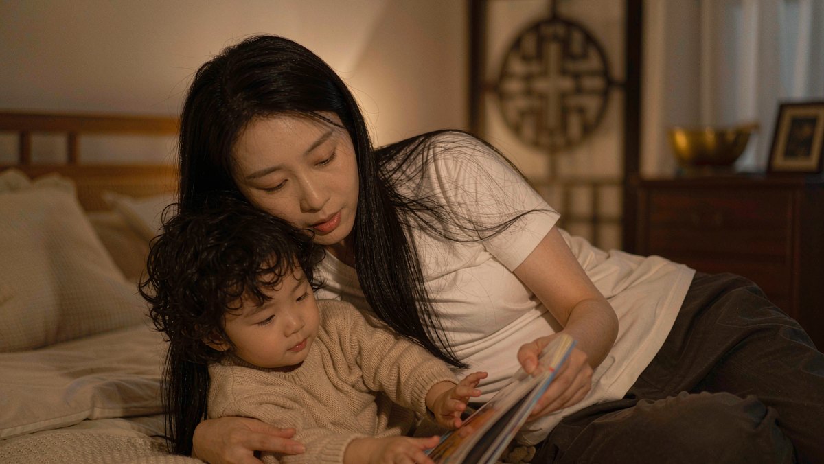 亲子依偎在床头,孩子安静地翻着一本他喜欢的绘本