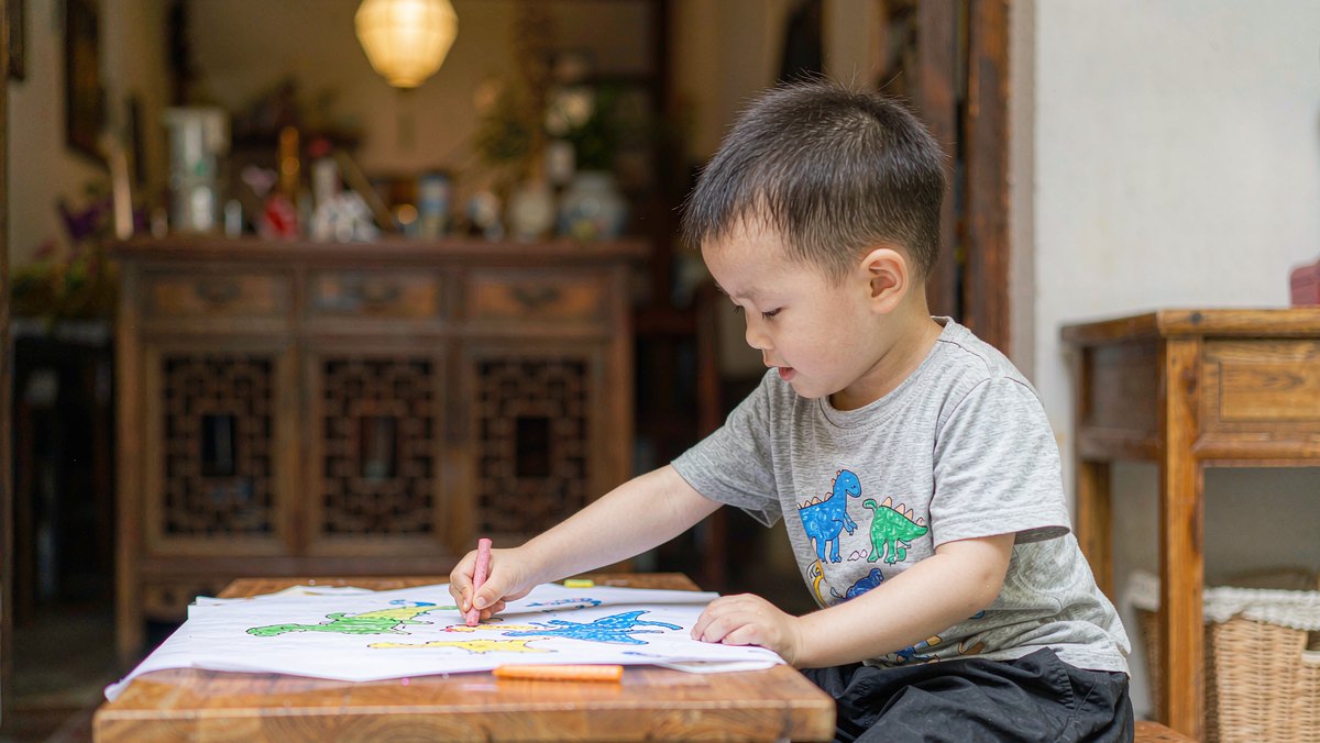 孩子拿着笔在纸上画自己编的故事结局