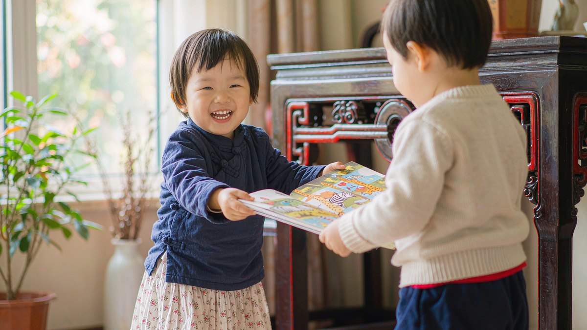 孩子主动把书递给小伙伴看
