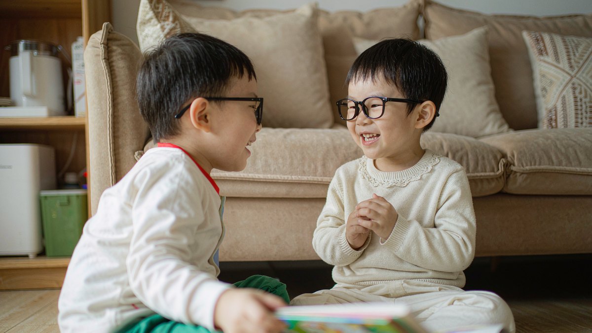 两个孩子一起开心地看同一本绘本
