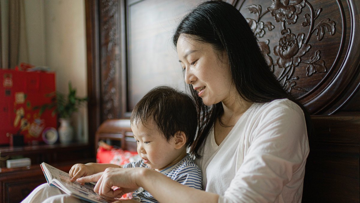 孩子指着绘本某一页向妈妈提问