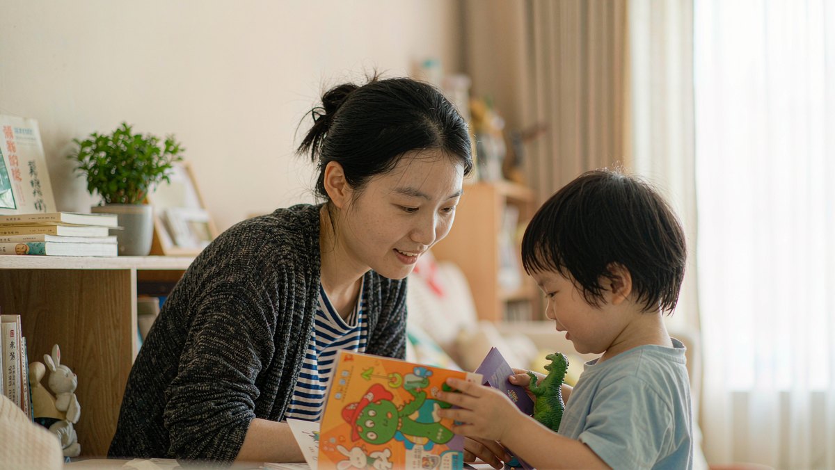 妈妈笑着听孩子讲绘本里小动物编的故事