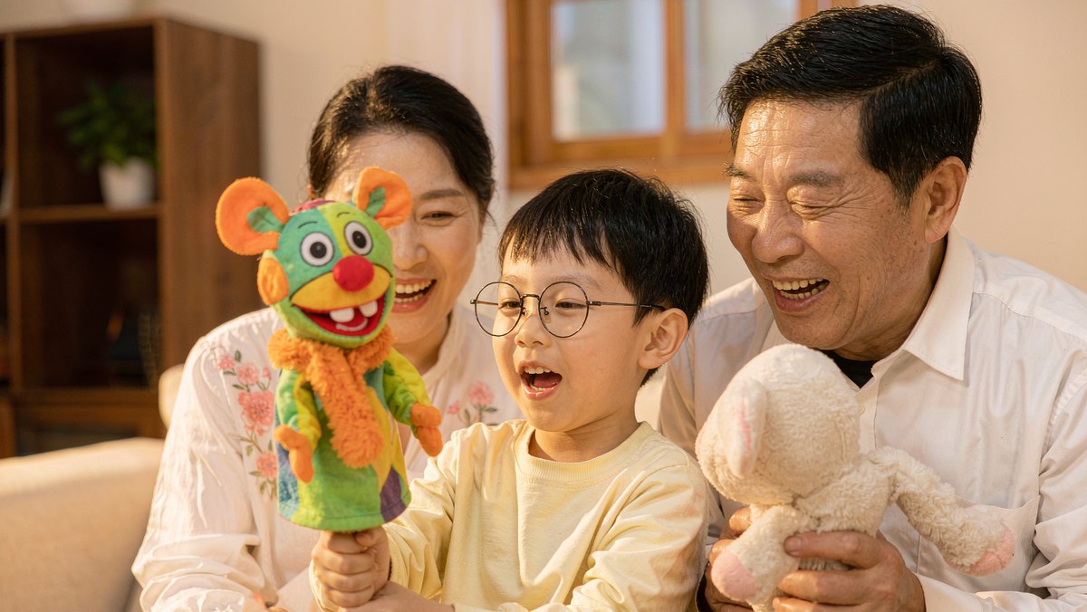 孩子和父母用手偶演绘本故事大笑