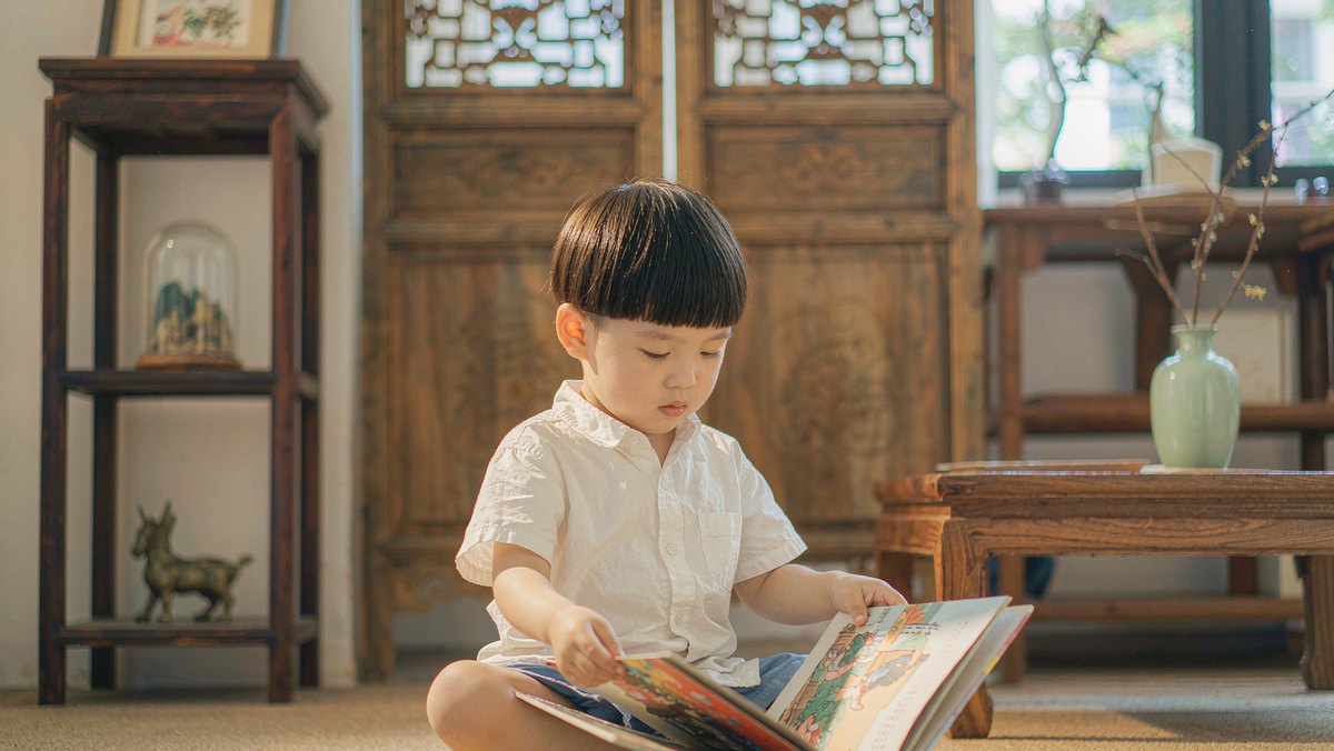 孩子自己抱着一本绘本坐在地毯上翻看