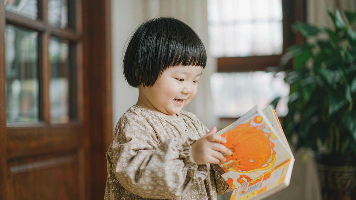 孩子手里拿着厚页纸板书开心地翻看