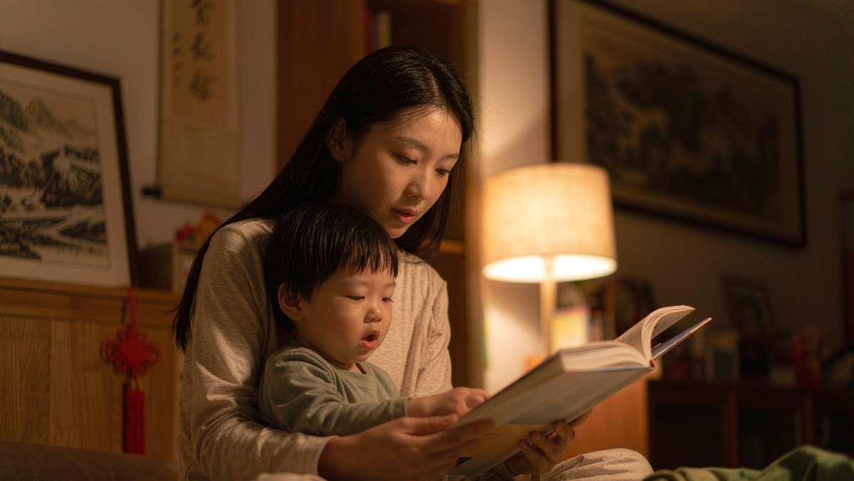 妈妈和孩子在灯下认真地共读一本绘本