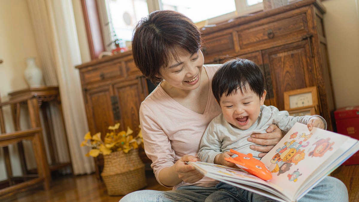 孩子和妈妈一起哈哈大笑看着绘本的欢乐瞬间