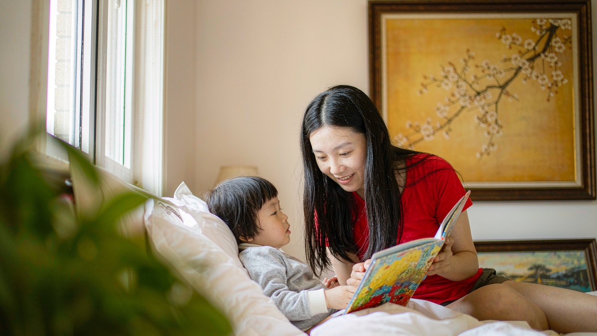 妈妈在床边陪孩子读一本熟悉的绘本