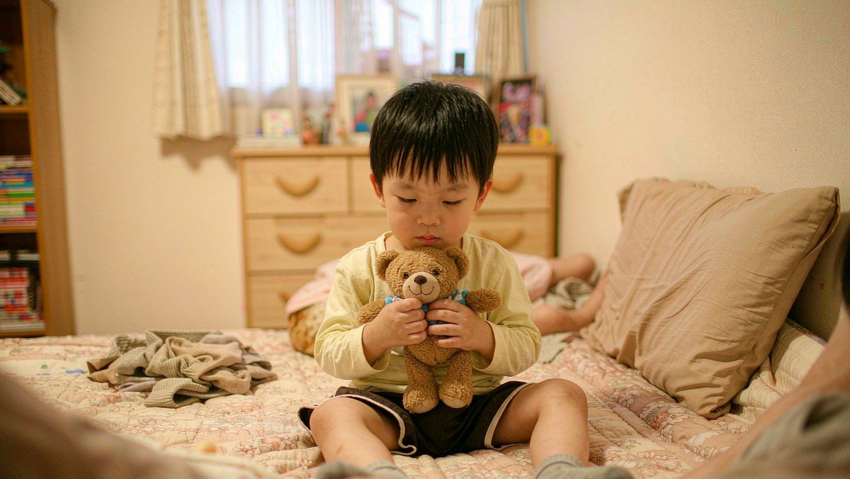 孩子抱着绘本里怕打雷的小熊玩偶