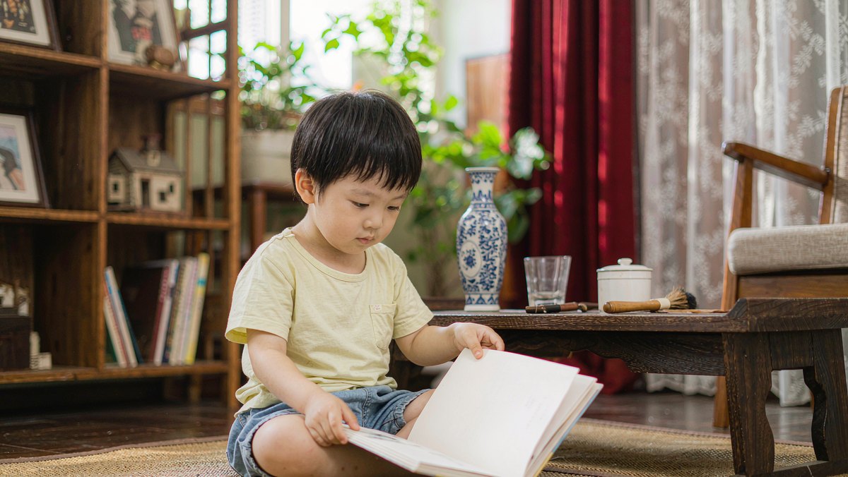 孩子坐在地垫上专注翻一本绘本