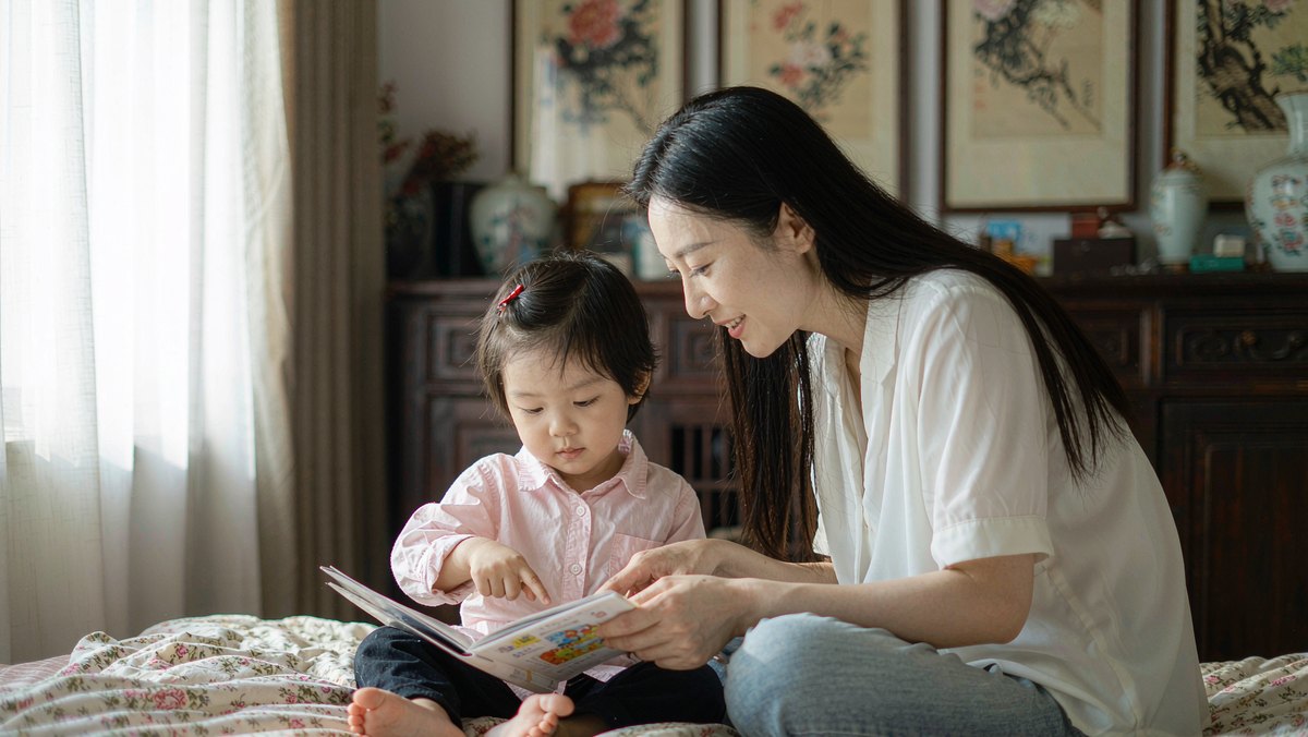 孩子用手指着绘本里的小角落给妈妈看
