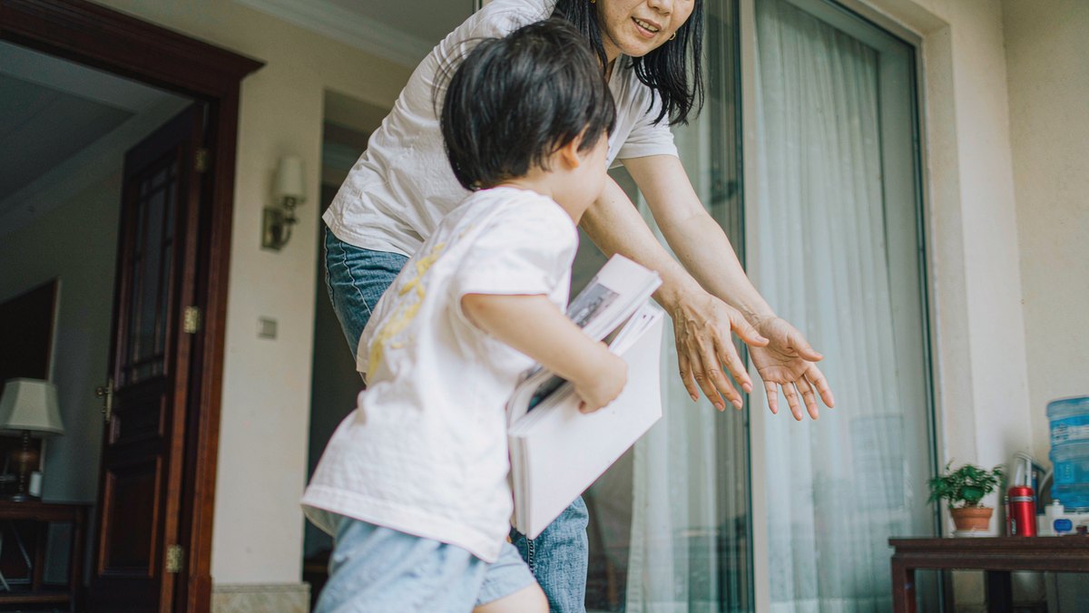 孩子举着纸质绘本跑向妈妈要一起读