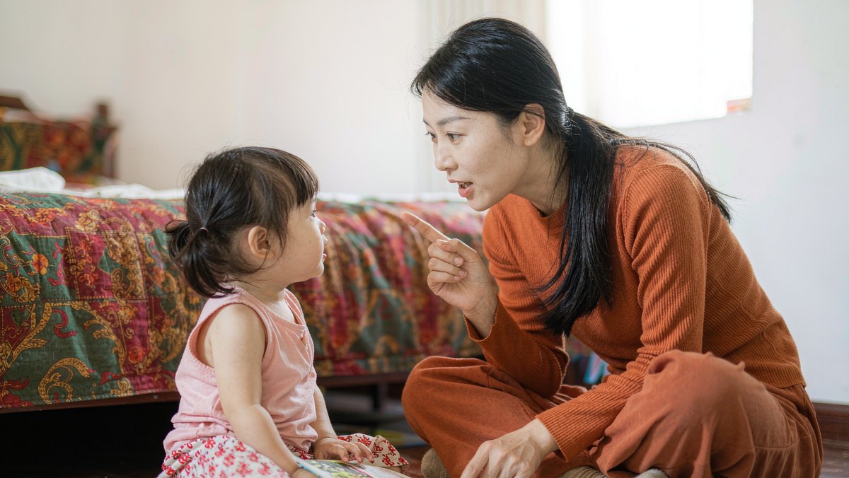妈妈和孩子面对面翻书时认真交谈