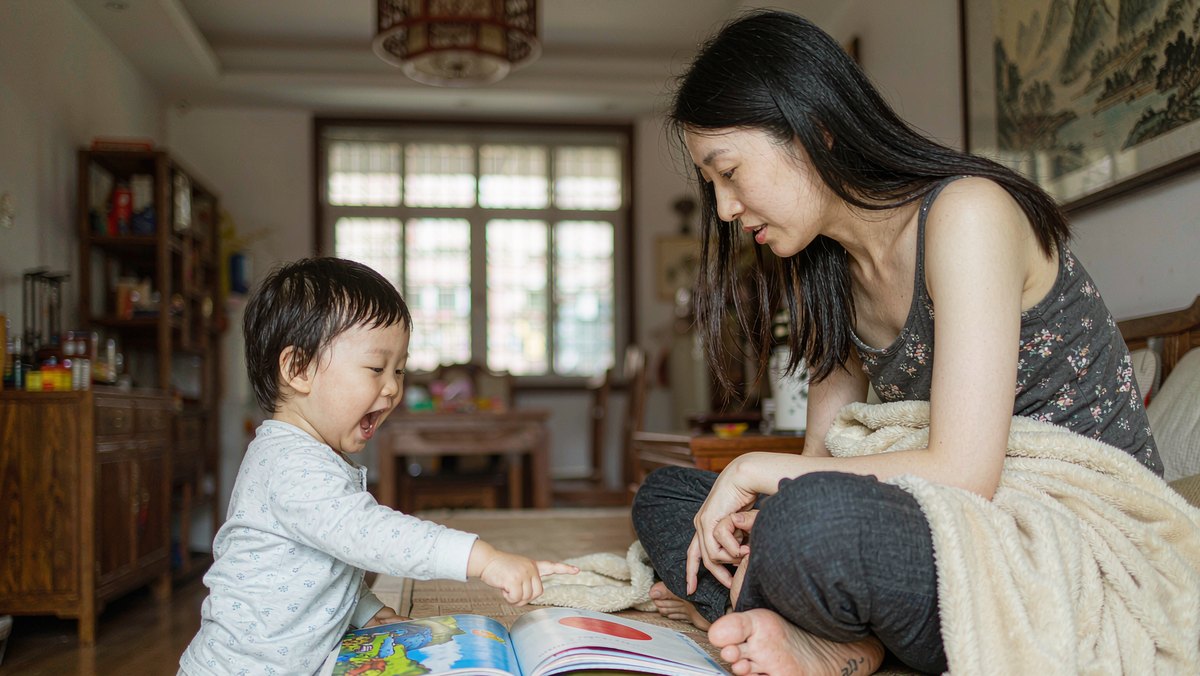 孩子指着绘本某一页兴奋地让妈妈细看