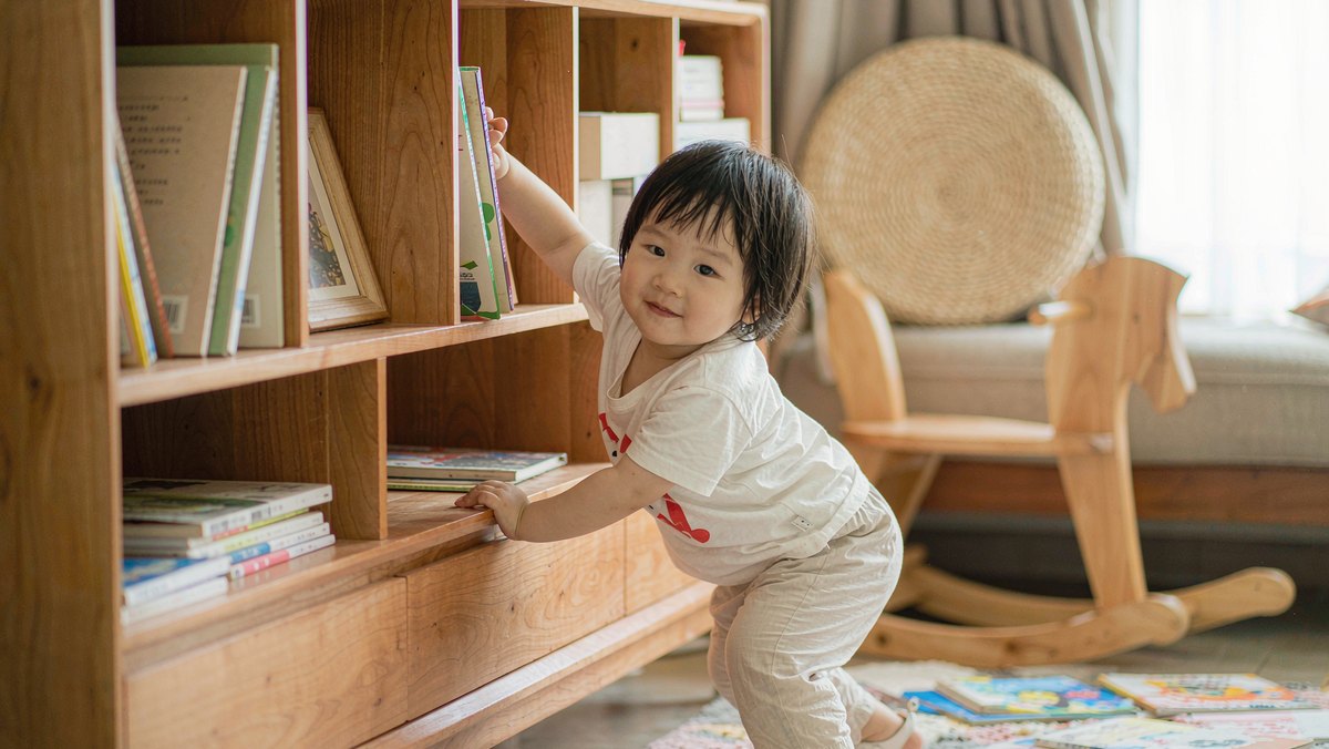 孩子踮脚把绘本一本本放进低矮书架